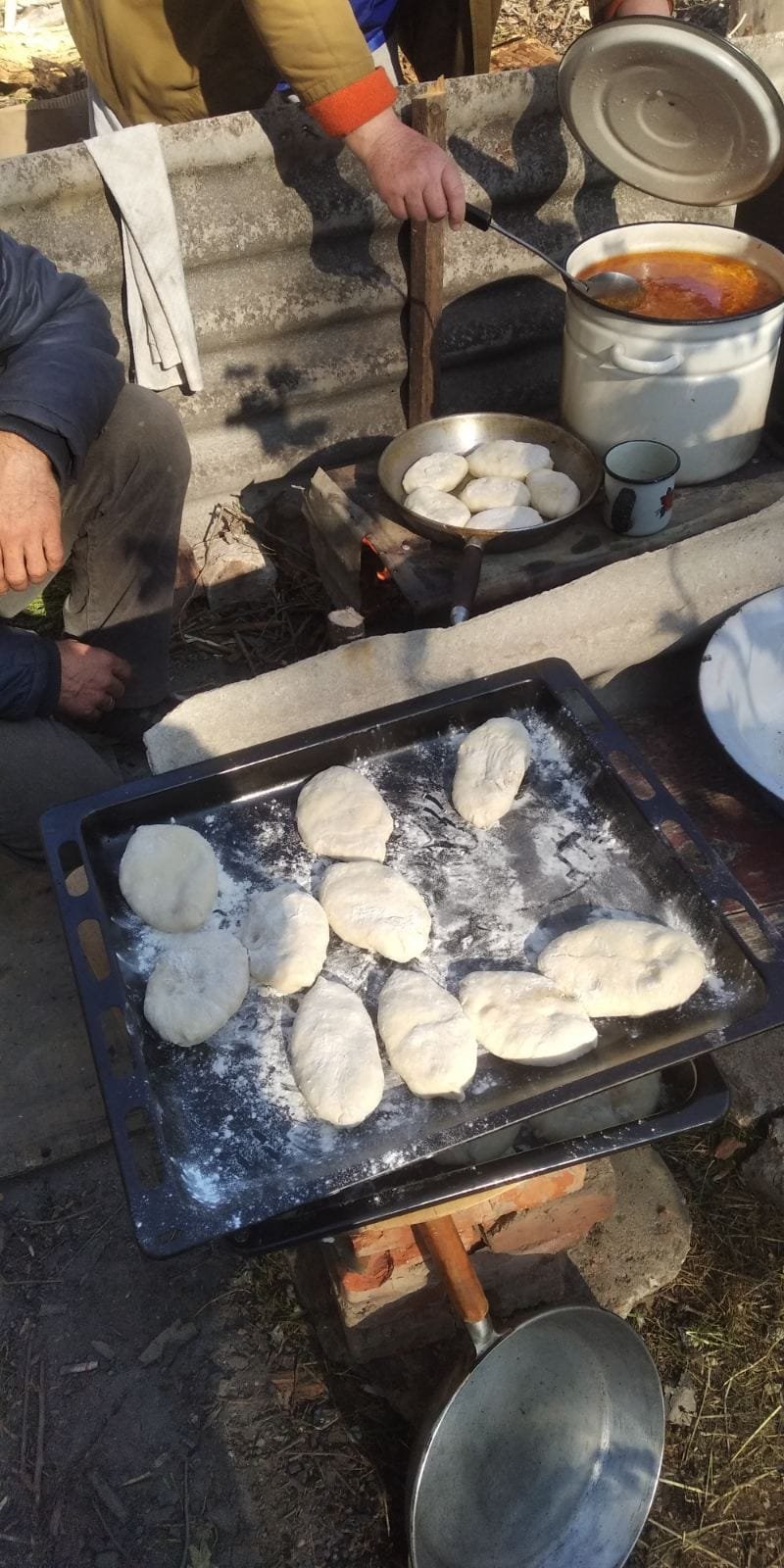 Жителі пошкоджених обстрілами багатоповерхівок в Оріхові змайстрували піч у дворі: готують борщ та пиріжки